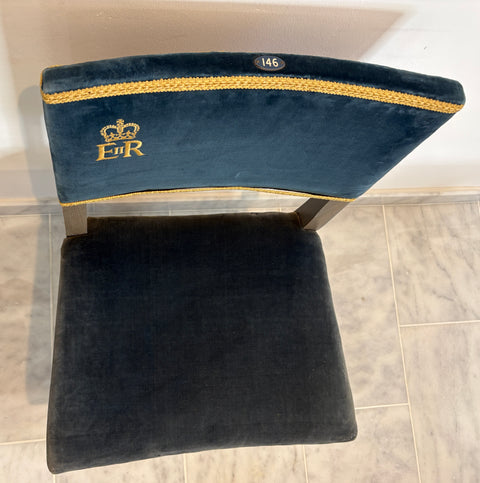 Navy blue cushion with gold trim and 'ER'  on a tiled floor.