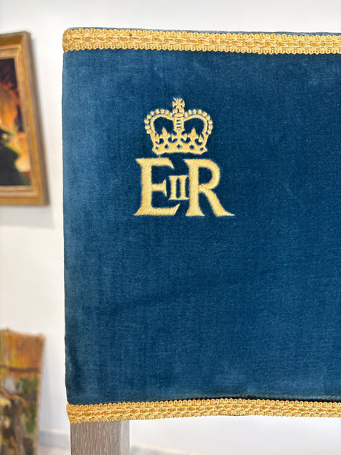 Blue velvet cushion with gold embroidery featuring a crown and 'ER' initials on a white background.