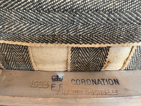 Close-up of a woven product with '1953 Coronation' branding on a wooden surface.